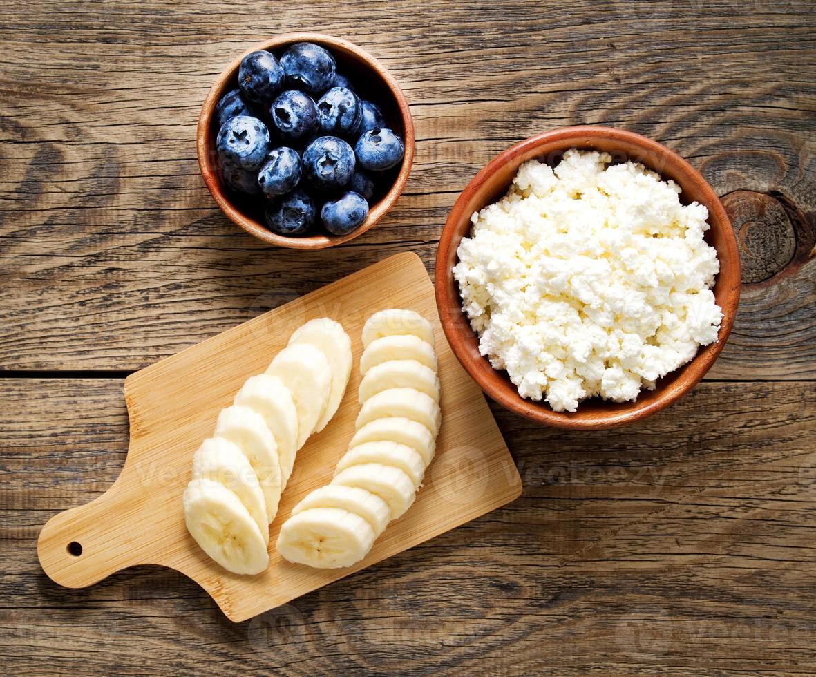 Brown wooden Bowl of homemade curd with banana, jam, blueberries photo