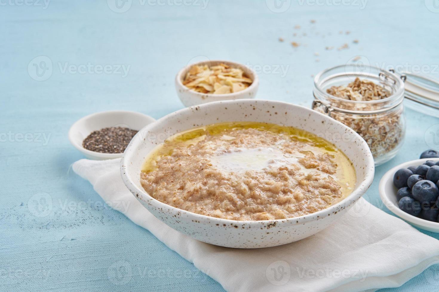 avena con mantequilla y coberturas. arándanos, semillas de chía, hojuelas de almendras, plátano. vista lateral foto