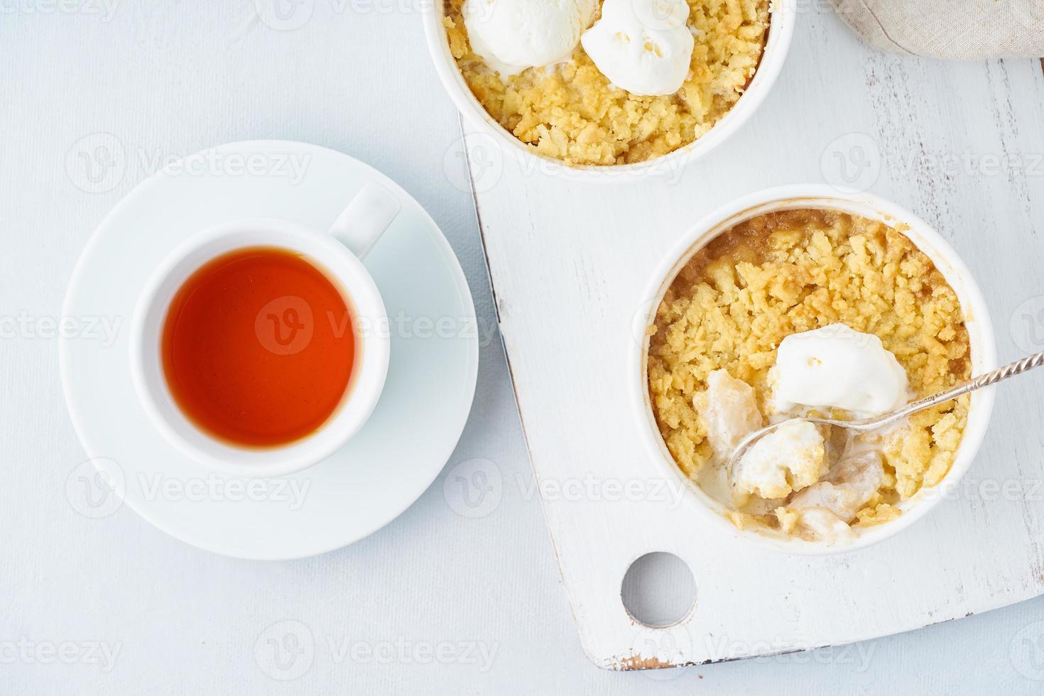 Apple crumble with ice cream, streusel. Morning breakfast with tea on a light gray table photo