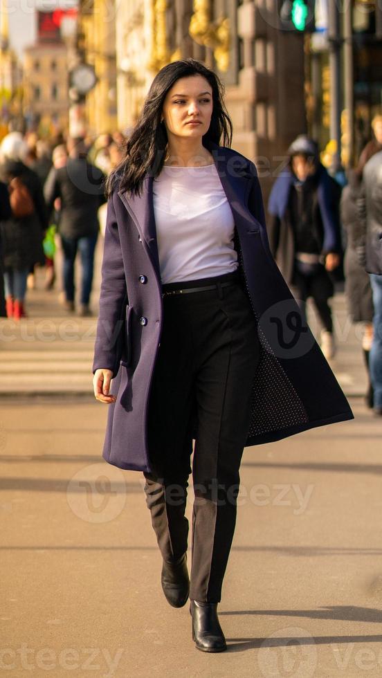 Beautiful serious smart brunette girl walking down street of St. Petersburg in city center. Charming thoughtful woman with long dark hair wanders alone photo