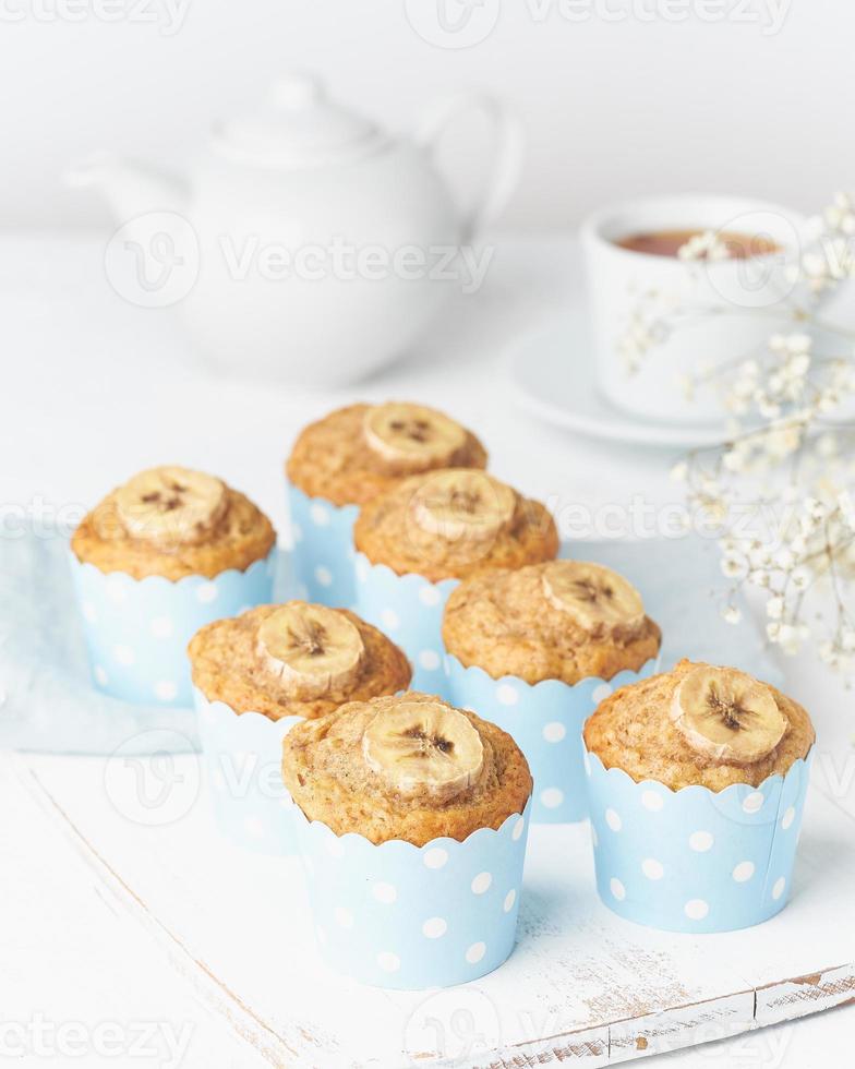 muffin de plátano, magdalenas en papel de cajas de pastel azul, mesa de hormigón blanco foto