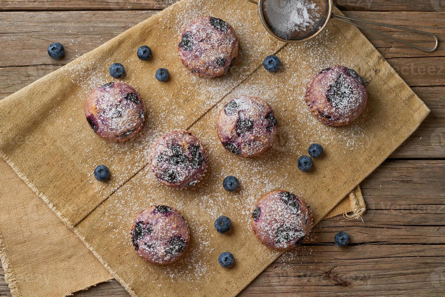 muffin de arándanos, vista superior. pastelitos con bayas en una vieja servilleta de lino rústico, mesa de madera foto