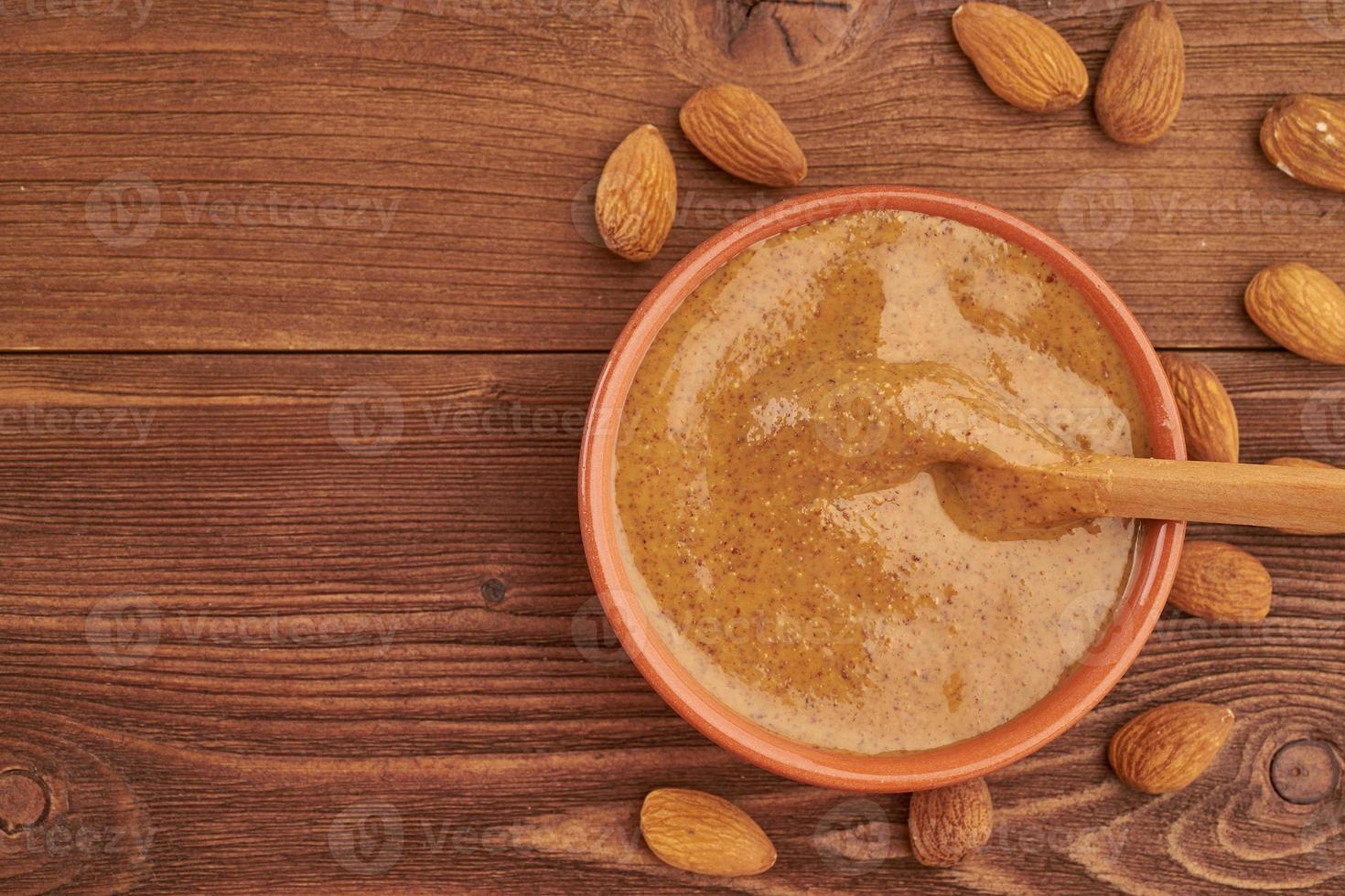 mantequilla de almendras, pasta de alimentos crudos hecha de almendras molidas en mantequilla de nuez, crujiente y revuelta, mesa de madera de color marrón oscuro, espacio para copiar, vista superior foto