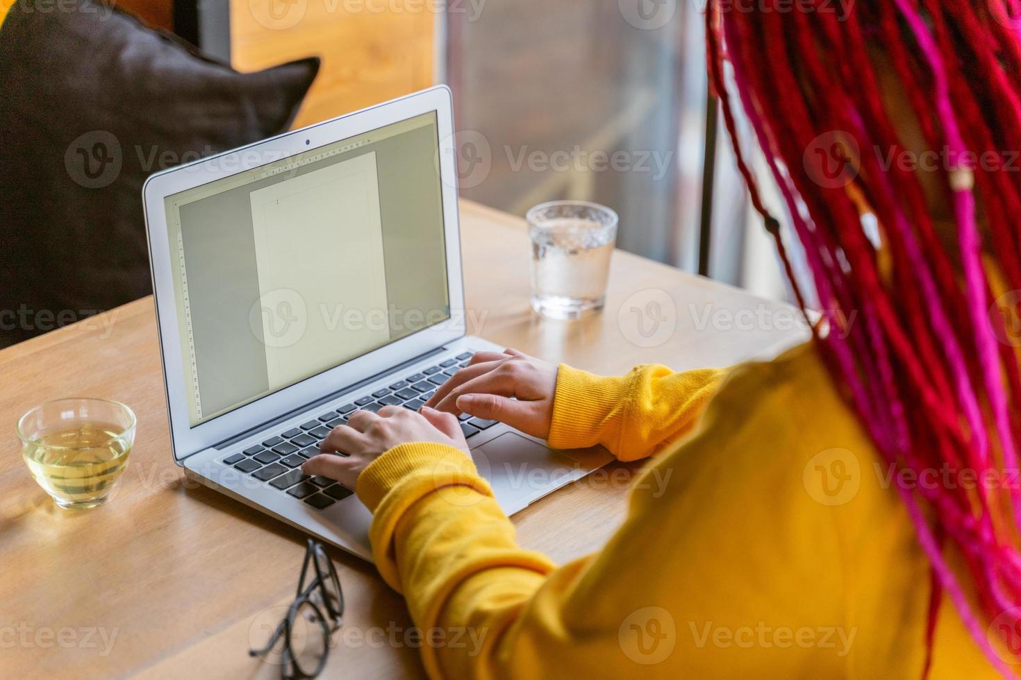 concepto de nómada digital. chica independiente que trabaja de forma remota en una computadora portátil en un café, coworking. foto