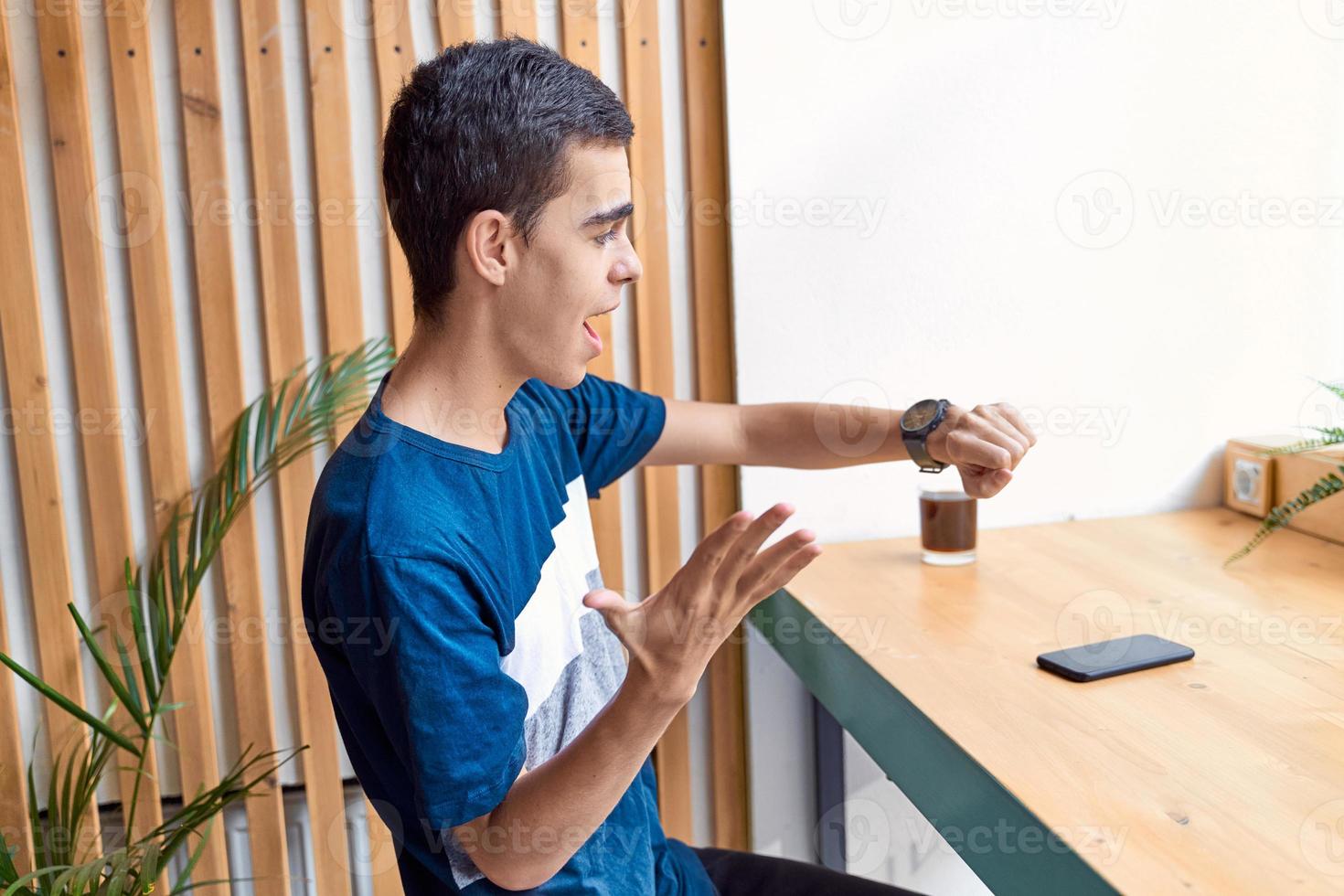 adulto joven mira el reloj. hombre caucásico estresado con cabello negro con miedo de llegar tarde. la chica llega tarde a una cita foto