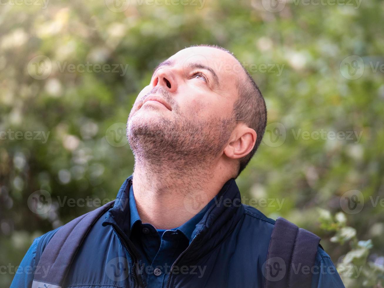 brunette man stands in the forest in nature and looks up photo