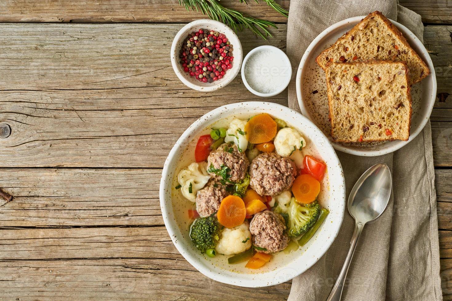 meatballs soup in white plate on old wooden rustic grey table, top view photo