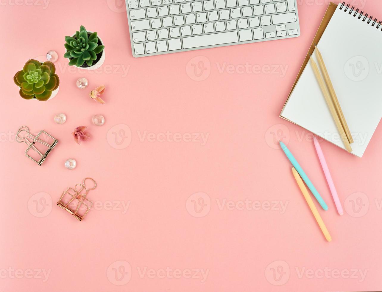 Top view of modern pink woman office desktop with blank notepad, computer. Mock up, empty space. photo