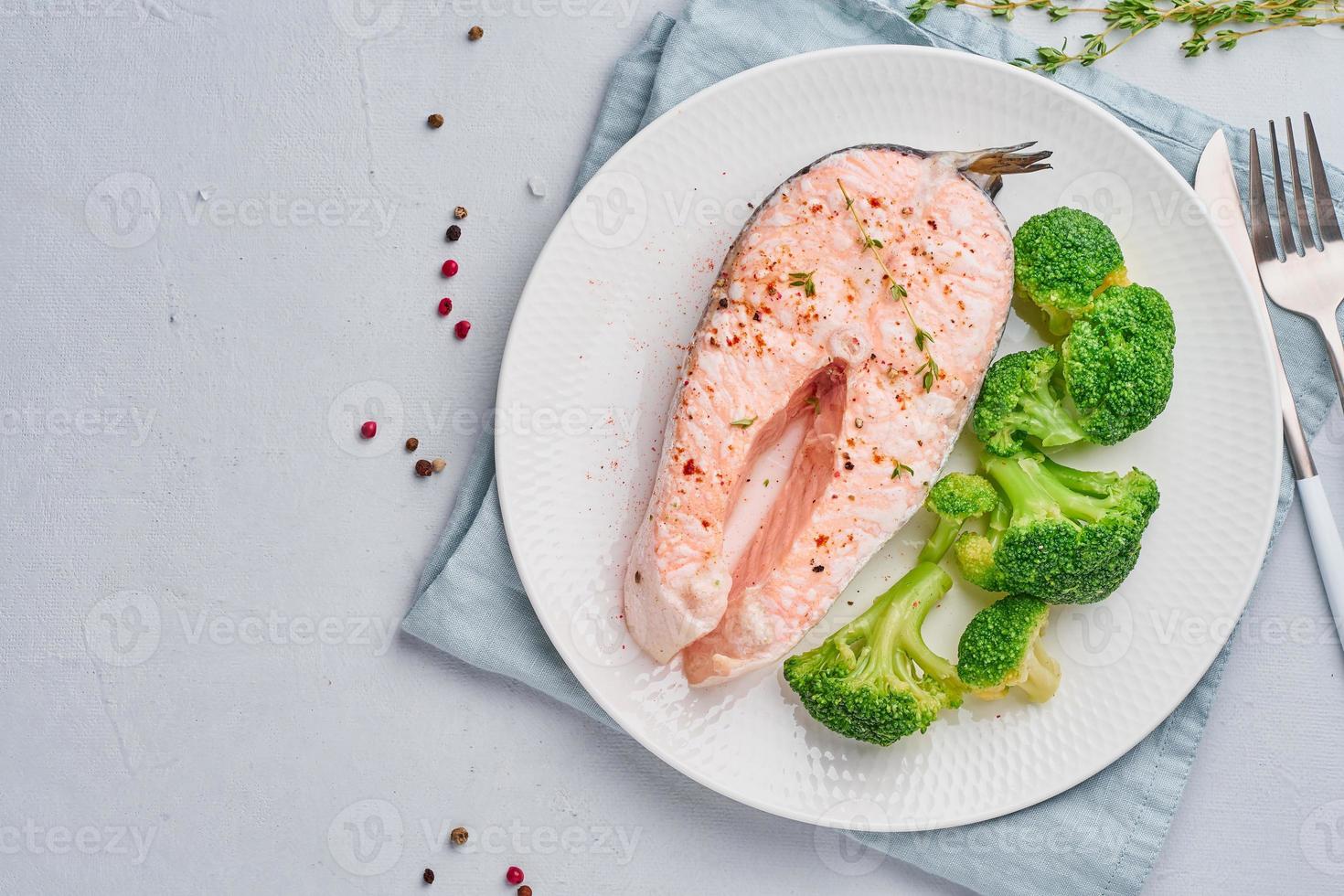 dieta de salmón al vapor, brócoli, paleo, ceto o fodmap. plato blanco sobre mesa azul, vista superior foto