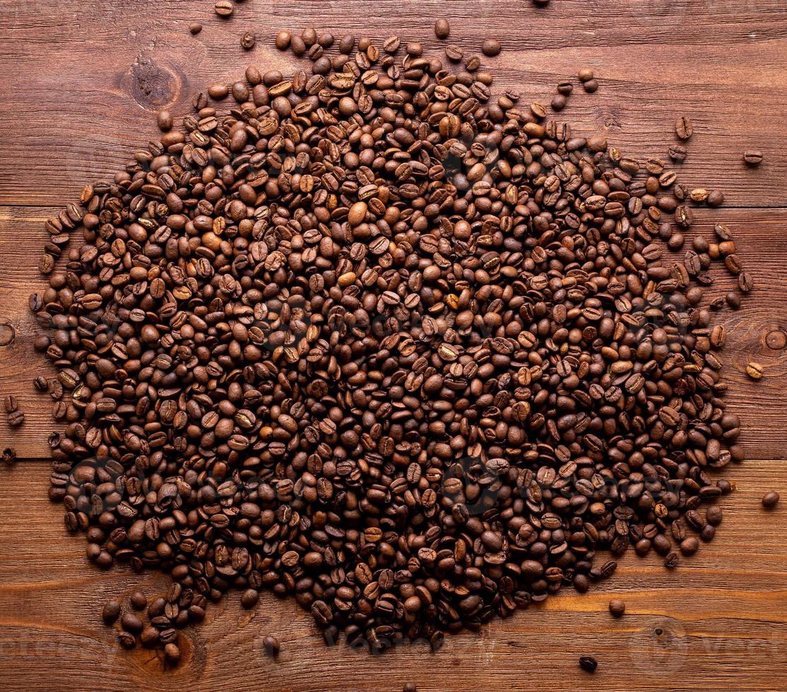 granos de café tostados de primer plano sobre fondo de madera marrón, vista superior, espacio de copia foto