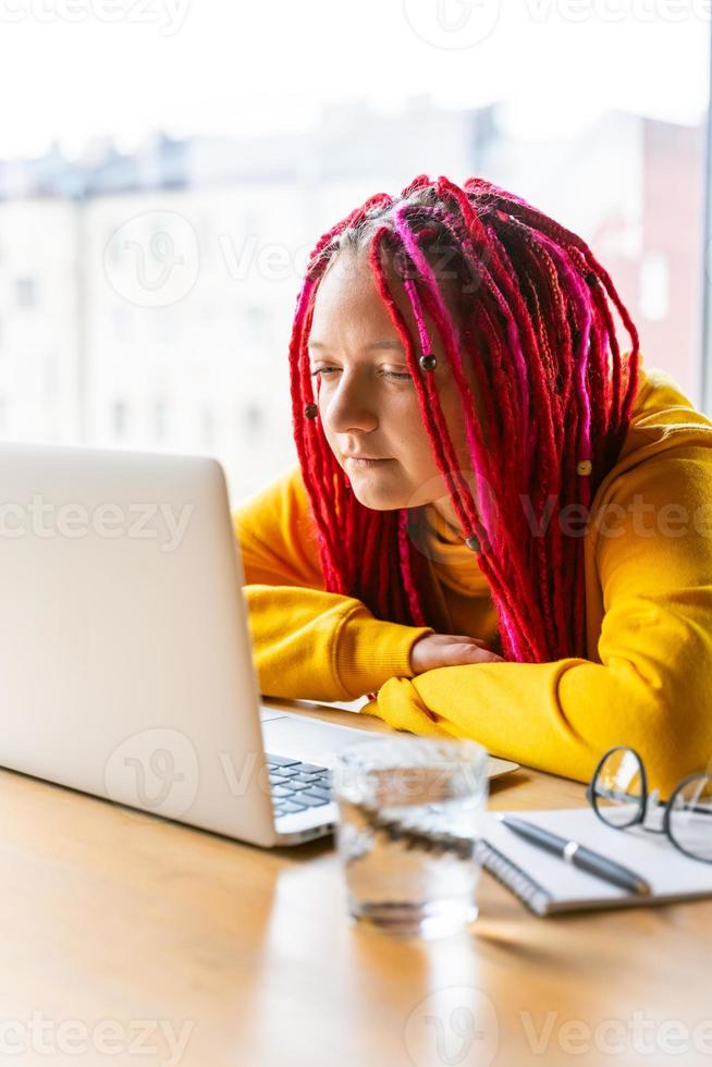 concepto de nómada digital. chica independiente que trabaja de forma remota en una computadora portátil en un café, coworking. foto