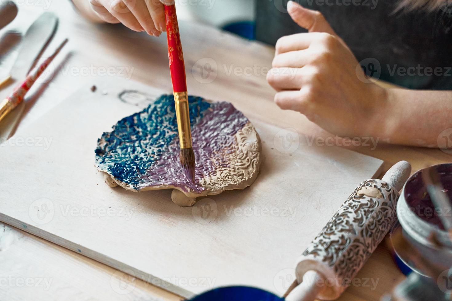 Unrecognised Woman making pattern on ceramic plate, hands close-up, focus on palms with paint brush. Creative hobby concept. Earn extra money, side hustle, turning hobbies into cash, passion into job photo