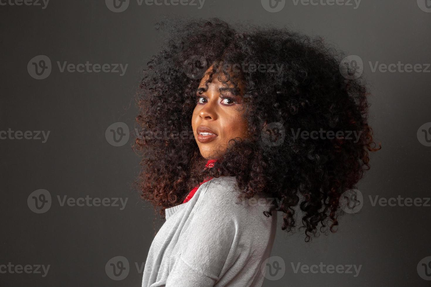 Beauty portrait of african american woman with afro hairstyle and glamour makeup. Brazilian woman. Mixed race. Curly hair. Hair style. Black background. photo