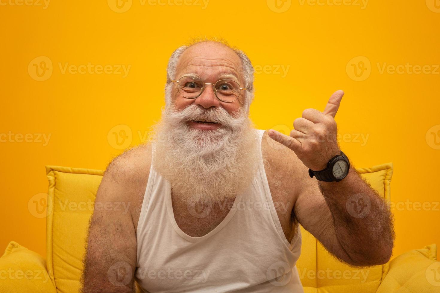 Old man with a long beard on a yellow background. Hang Loose. Senior with full white beard. Old man with a long beard with sadness. photo