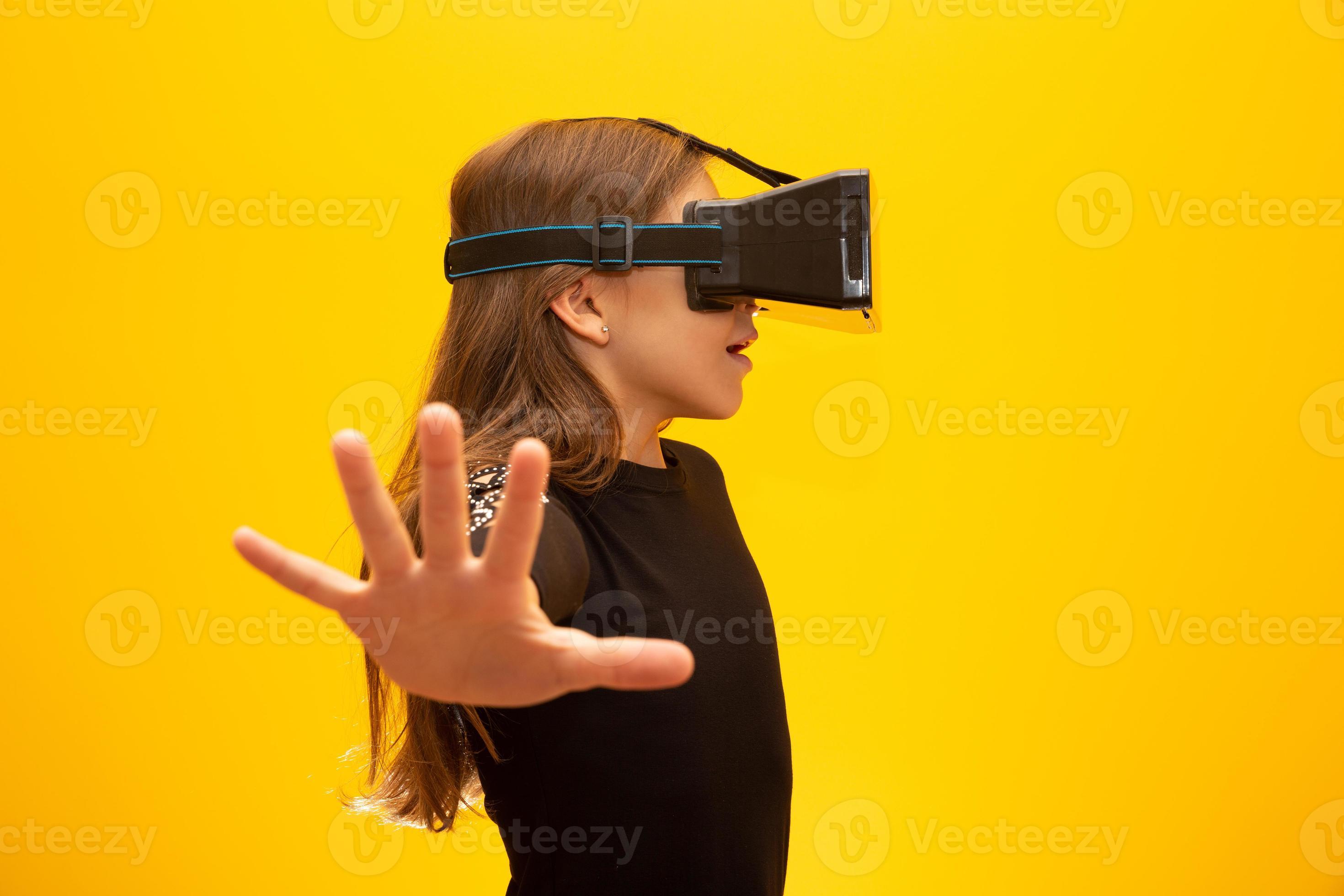 Kvinde Vores firma Besiddelse Happy little girl wearing virtual reality goggles watching movies or  playing video games. Cheerful smiling teenager looking in VR glasses. Funny  child experiencing 3D gadget technology - close up. 7547794 Stock Photo