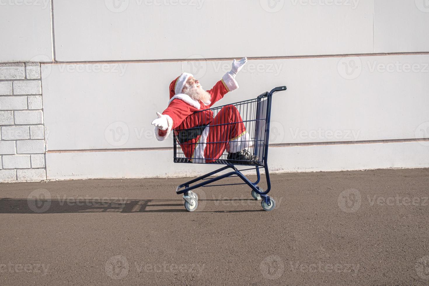 Supermarket cart with Santa Claus inside. Shopping for Christmas concept. photo