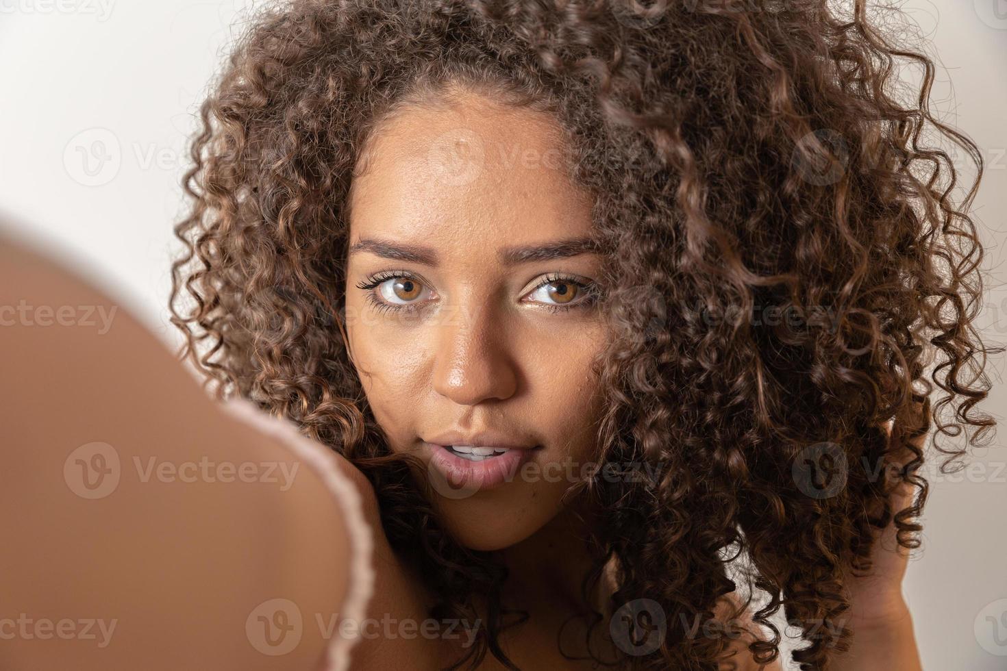 Selfie portrait of cheerful black woman in studio with curly hair photo