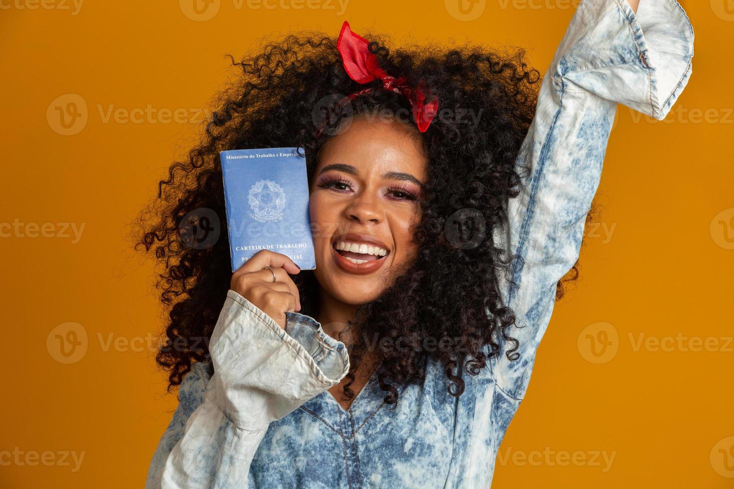 Beautiful curly-haired girl holding a work card. On yellow background. photo