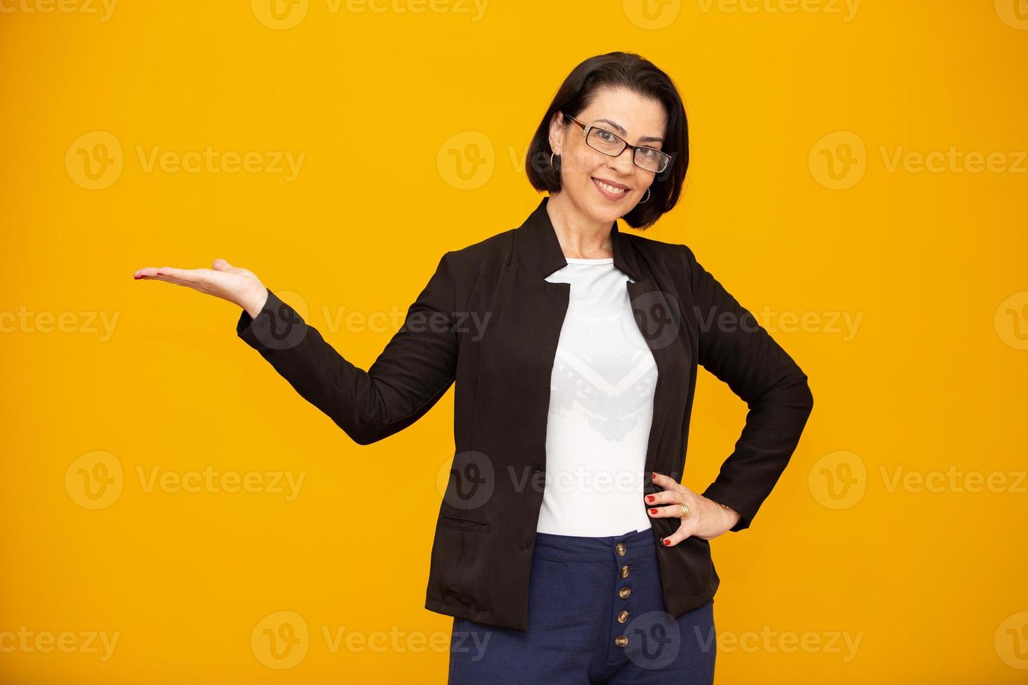 Beautiful middle age business woman smiling and looking at the camera pointing with hand to the side. photo