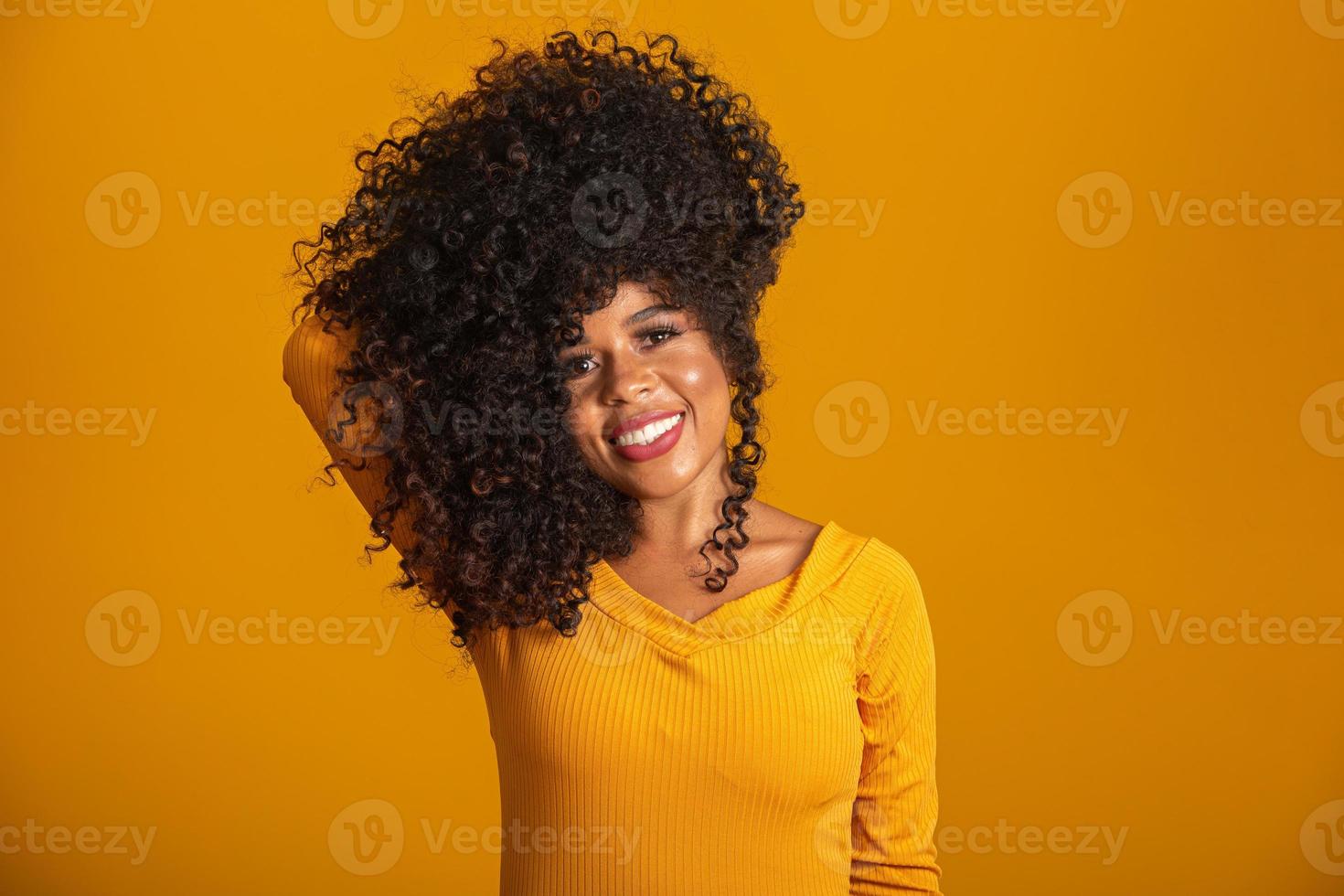 Young afro-american woman with curly hair looking at camera and smiling. Cute afro girl with curly hair smiling looking at camera. photo