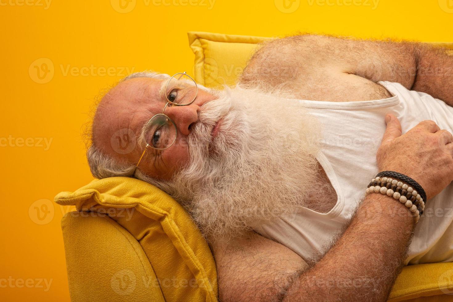 anciano con una barba larga sobre un fondo amarillo. senior con barba blanca completa. anciano con barba larga con tristeza. foto