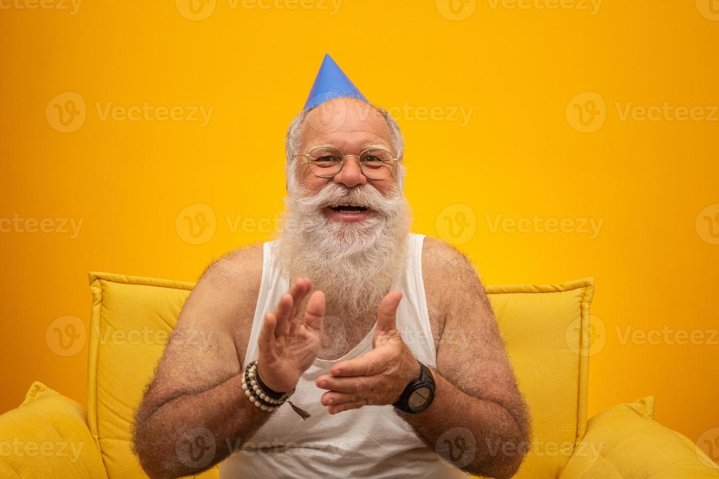 Positive elderly man in party hat smiling to camera, birthday celebration photo