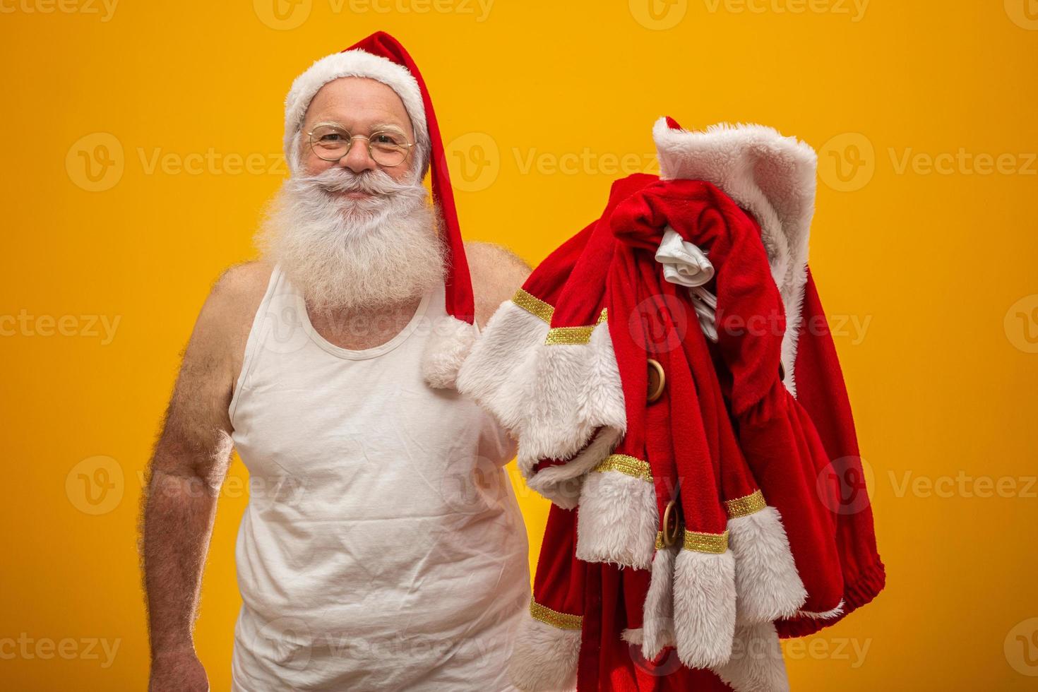 santa sosteniendo su ropa antes o después de entregar los regalos. la ropa de papa noel traje. foto