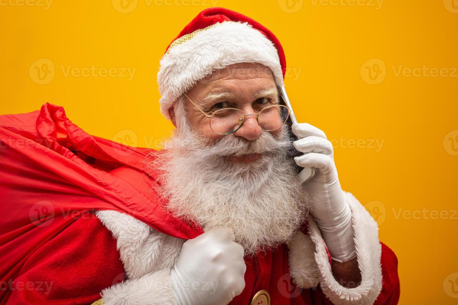 Holly jolly x mas Santa in headwear, costume, black belt, white gloves brings gifts for kids, prepared to celebrate, sale promotion, winter december, chatting on telephone. Santa talking on the phone photo