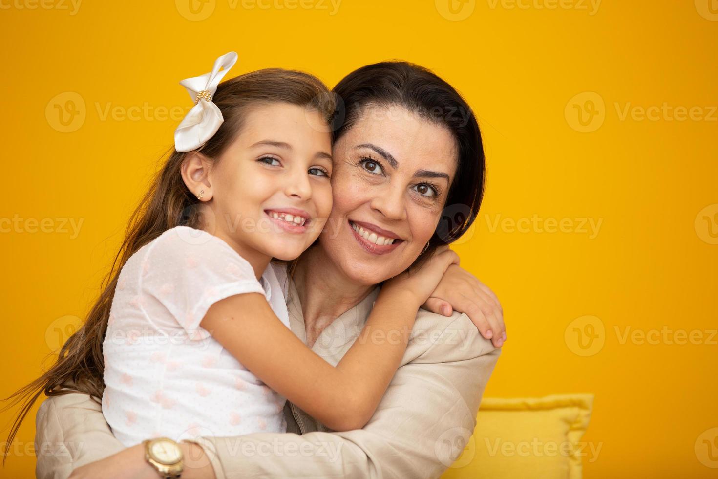 feliz día de la madre primer plano retrato de madre e hija bonitas y encantadoras con sonrisas radiantes sobre fondo amarillo. hija abrazando a la madre sobre fondo amarillo. foto