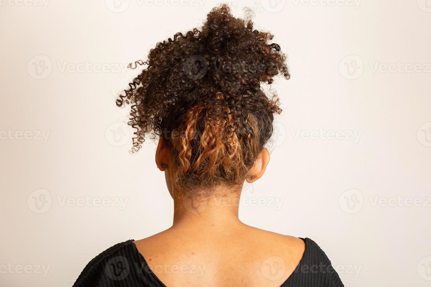 Young black woman on her back with afro hairstyle on white background. Girl with african hairstyle. Studio shot. photo