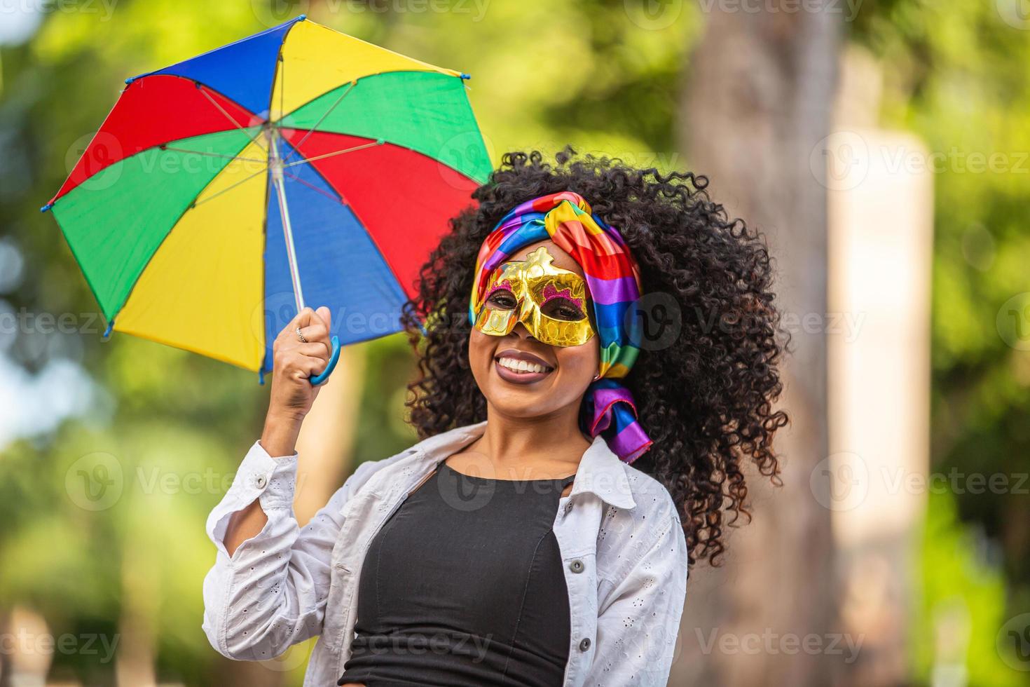 mujer joven de pelo rizado celebrando la fiesta del carnaval brasileño con paraguas frevo en la calle. foto