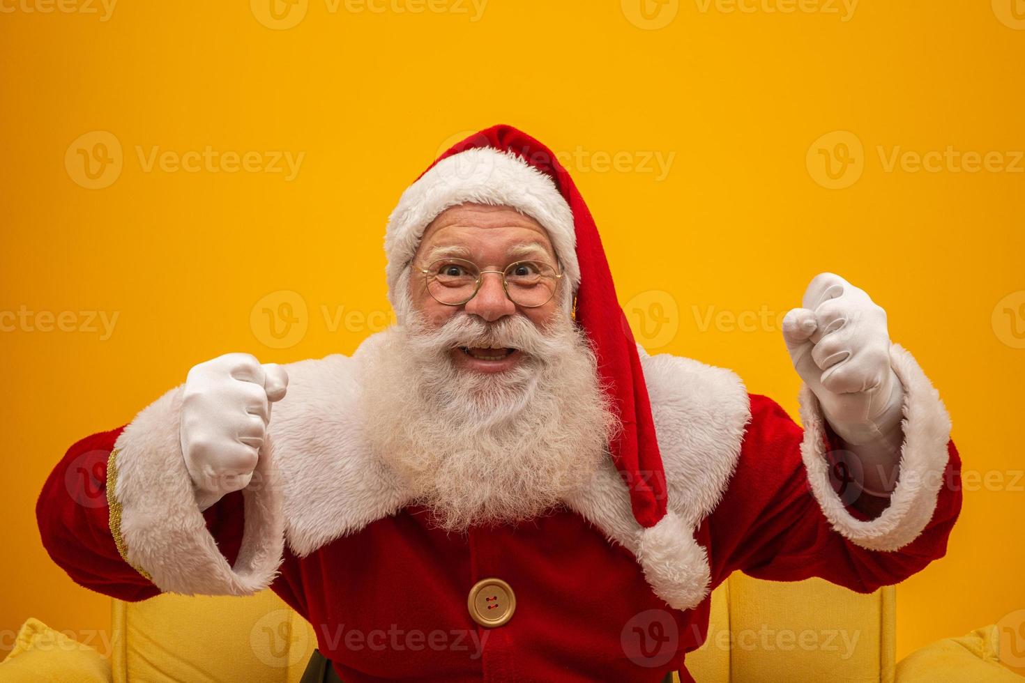 Holly jolly x-mas and Noel, confidence, magic, triumph concept. Cool funny playful grandfather with wide open mouth, comic grimace, fooling around isolated on yellow background, shows win gesture photo