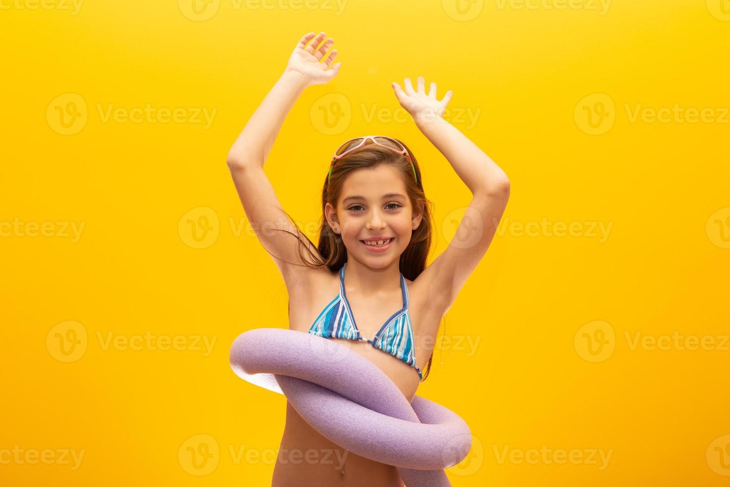 Child wearing bikini on yellow background. Concept of summer, beach and pool. photo