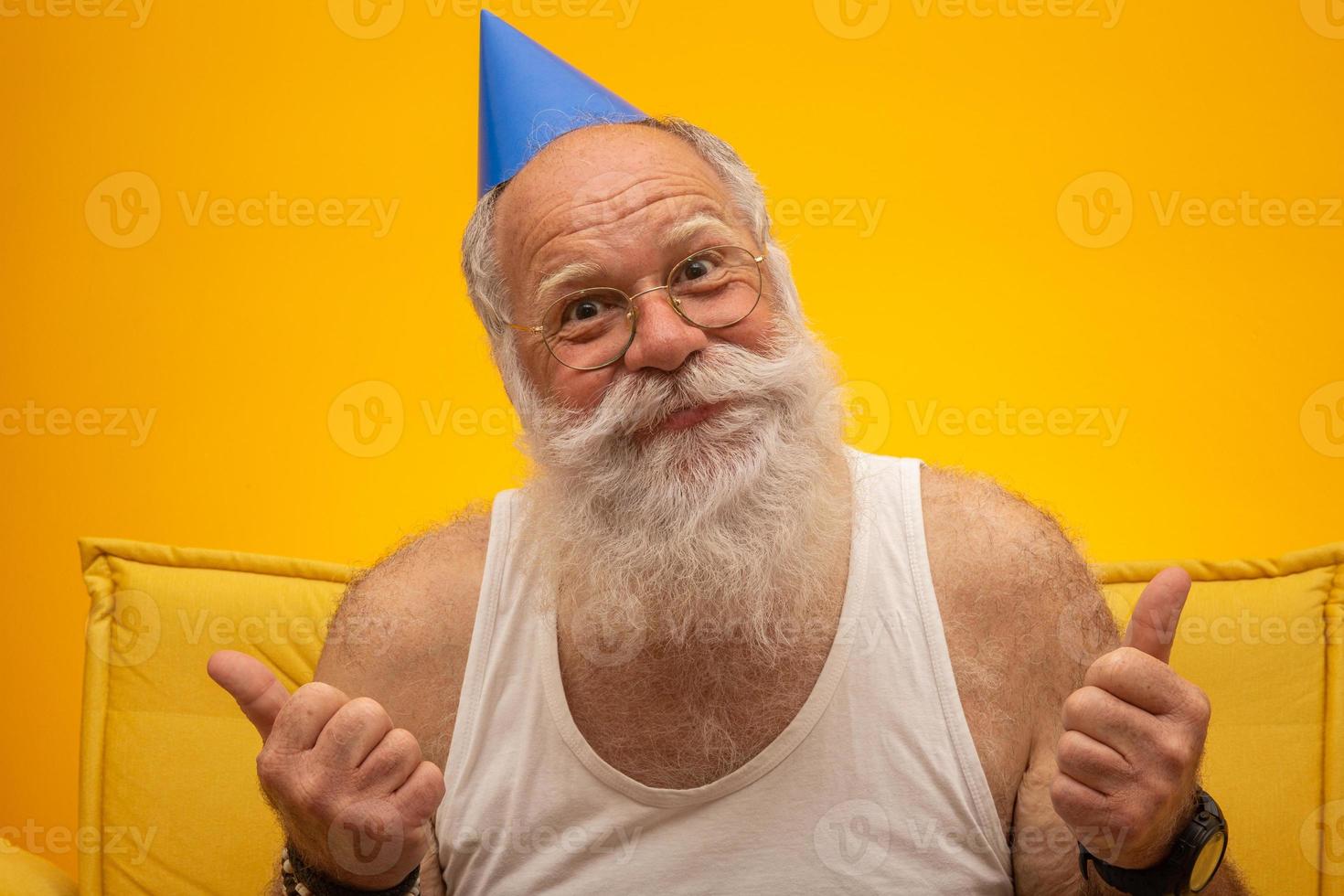 Positive elderly man in party hat smiling to camera, birthday celebration photo