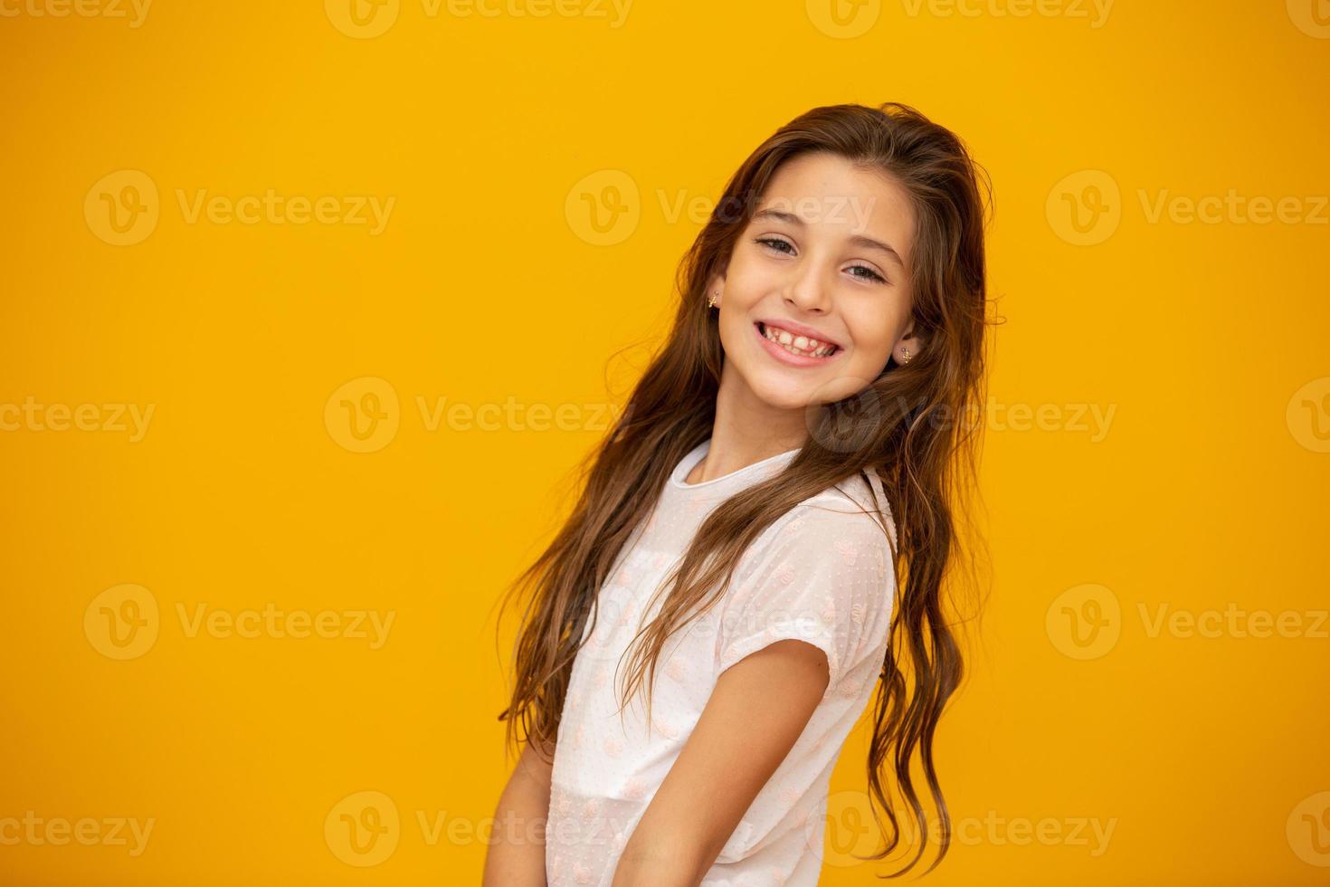 Portrait of a happy smiling child girl in yellow background. photo