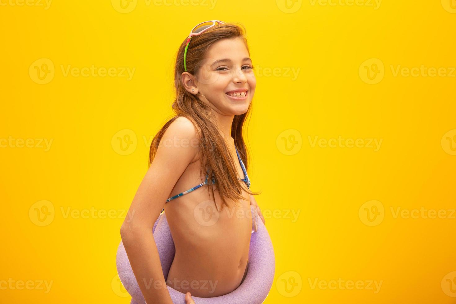Child wearing bikini on yellow background. Concept of summer, beach and pool. photo