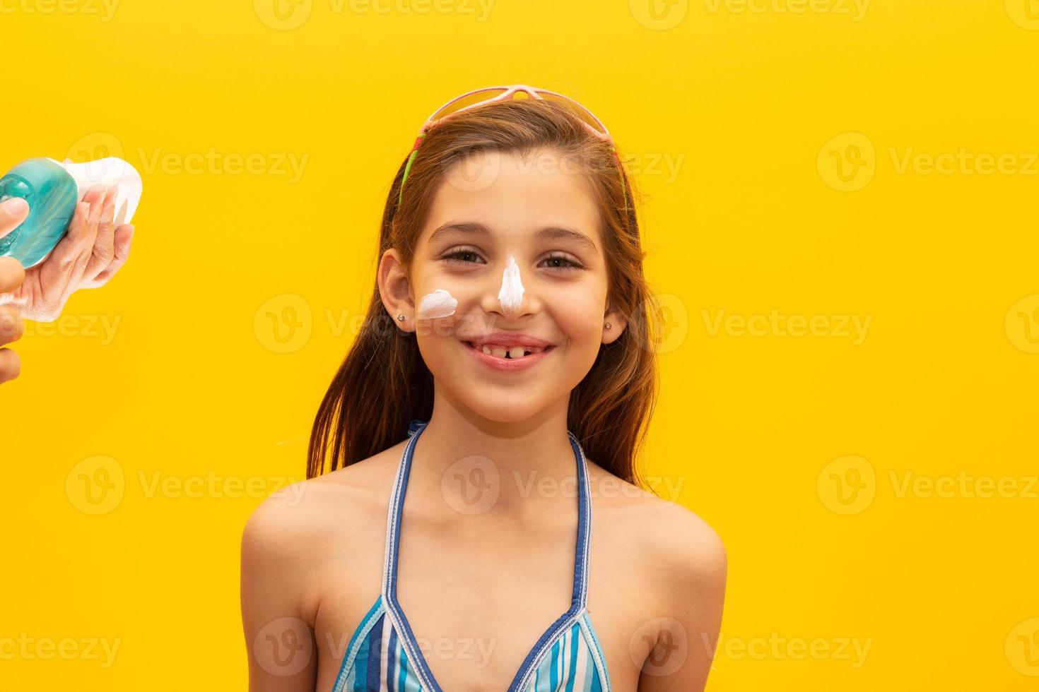 Child with sunscreen in her face. Concept of summer, beach and pool. photo