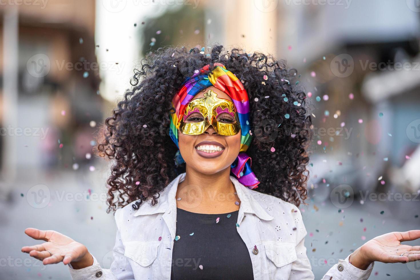 Carnaval party. Brazilian curly hair woman in costume blowing confetti photo