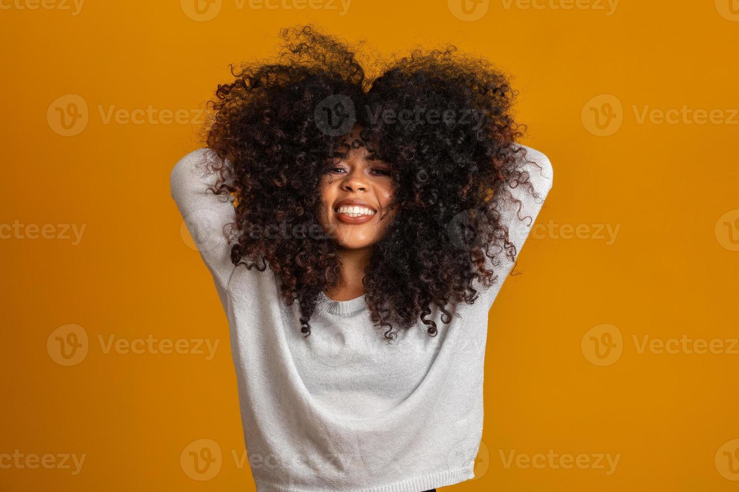 Beauty portrait of african american woman with afro hairstyle and glamour makeup. Brazilian woman. Mixed race. Curly hair. Hair style. Yellow background. photo
