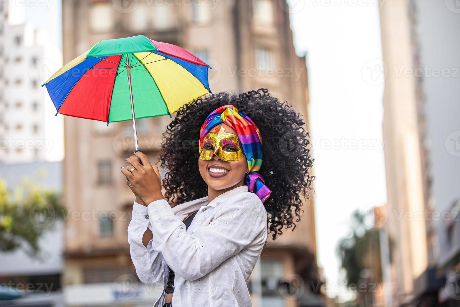 mujer joven de pelo rizado celebrando la fiesta del carnaval brasileño con paraguas frevo en la calle. foto