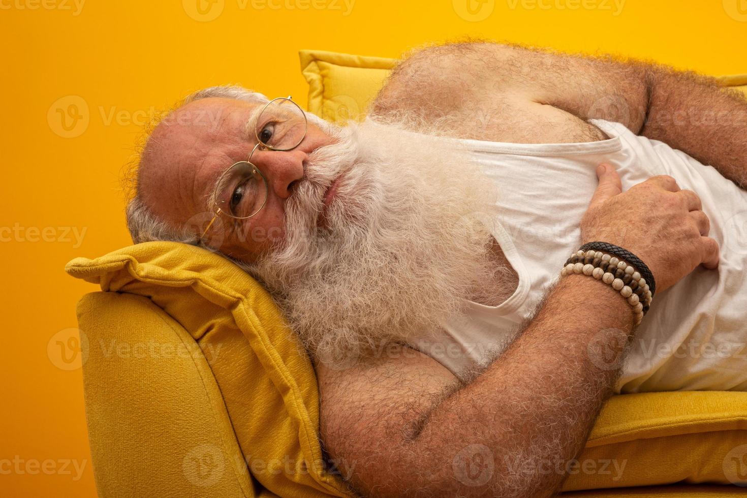 Old man with a long beard on a yellow background. Senior with full white beard. Old man with a long beard with sadness. photo