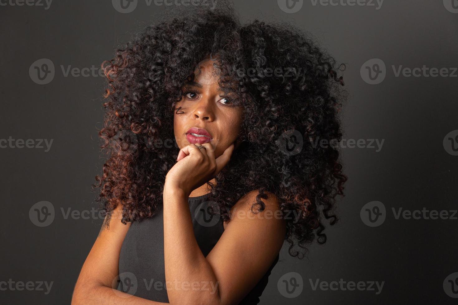 joven mujer afroamericana con cabello rizado mirando a la cámara y sonriendo. linda chica afro con cabello rizado sonriendo mirando a la cámara. foto