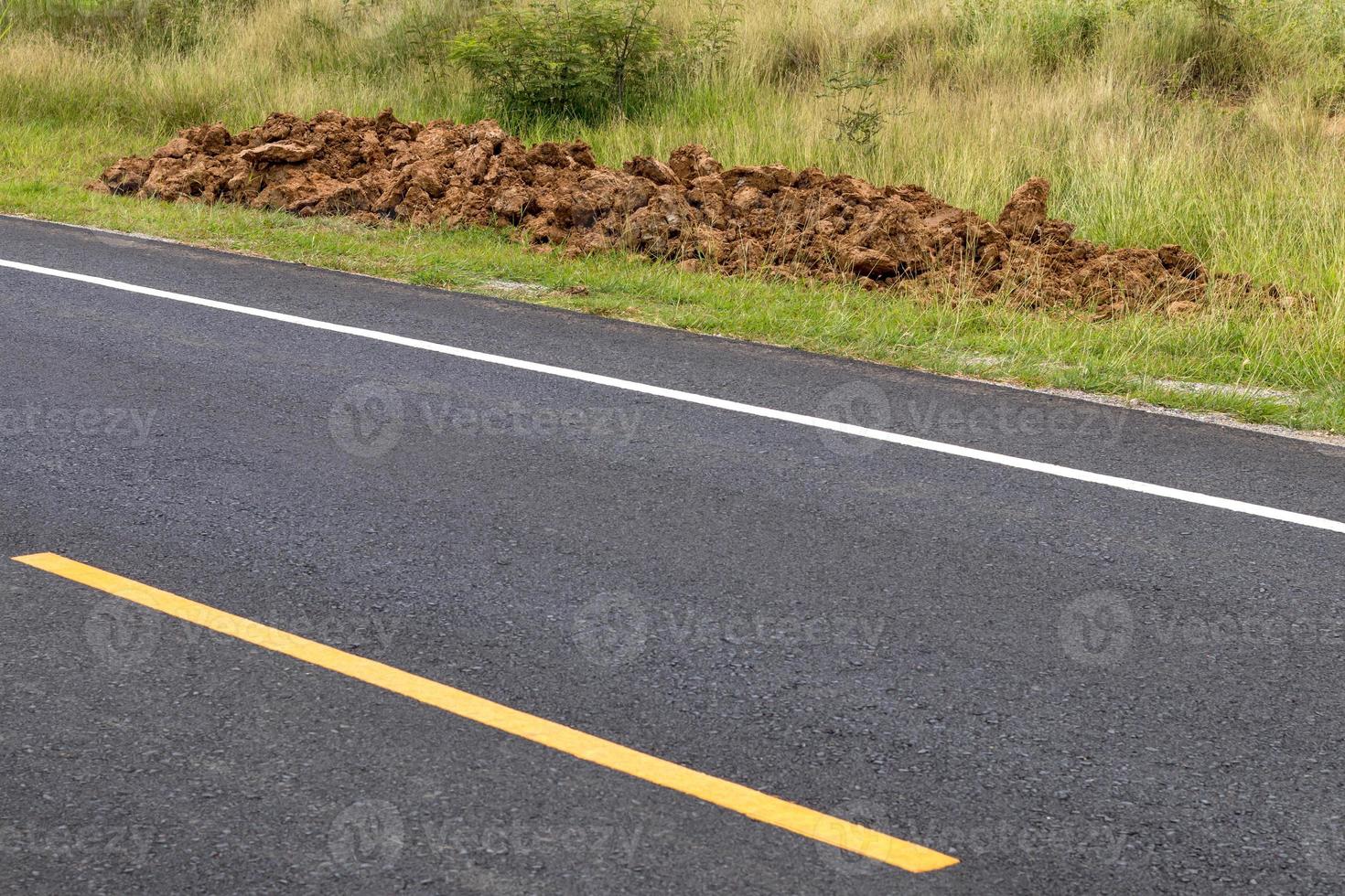 Asphalt road surface with a pile of dirt. photo