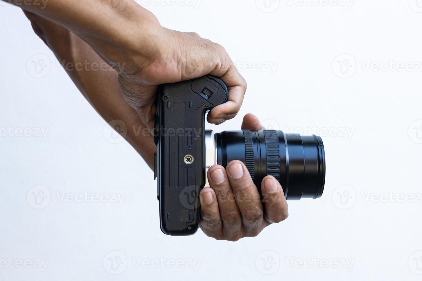Isolated close-up of the hands and fingers of a Thai man holding an old black DSLR film camera. photo