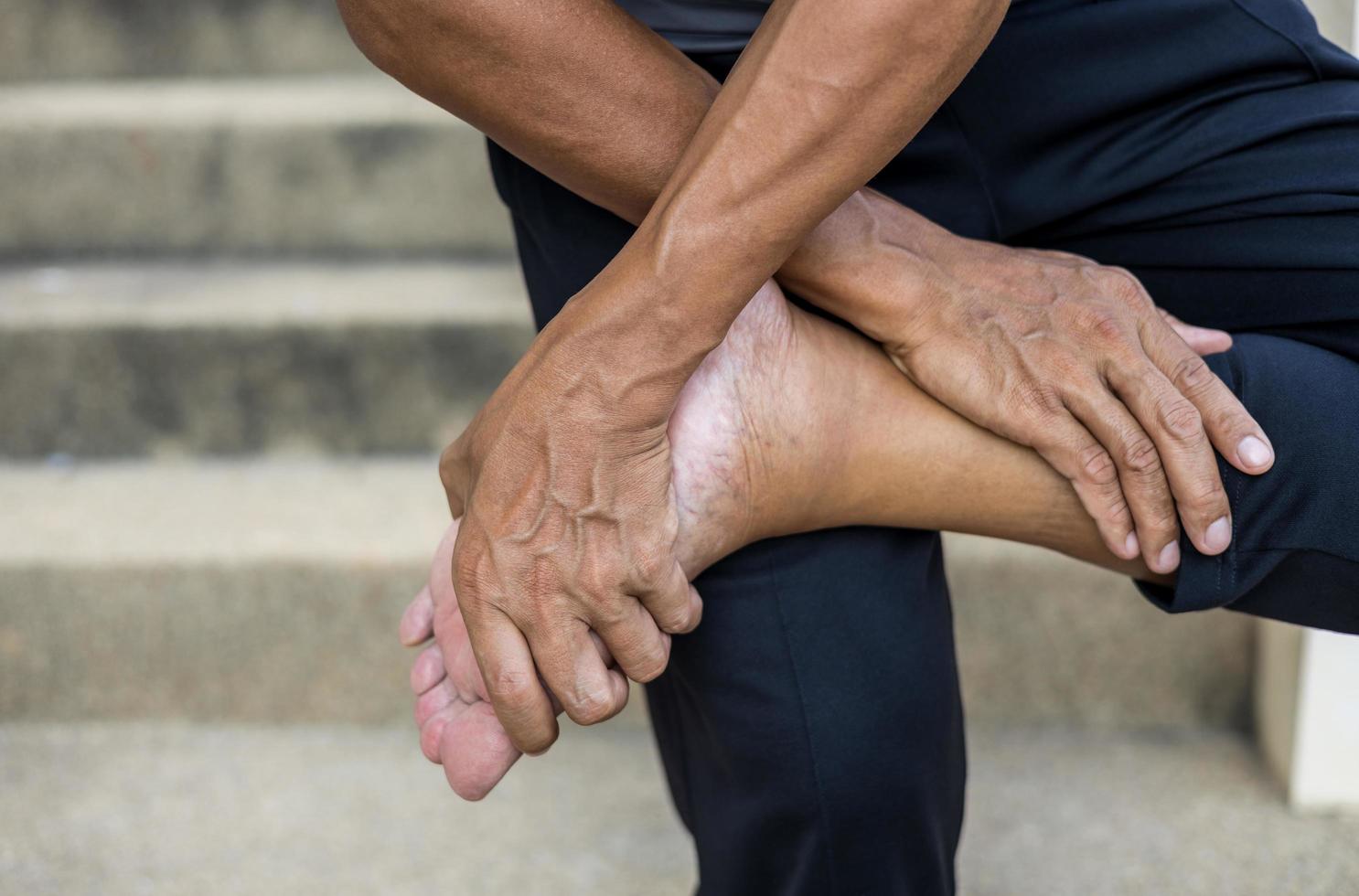 primer plano de la mano de un hombre tailandés de pie y sosteniendo sus pies. foto