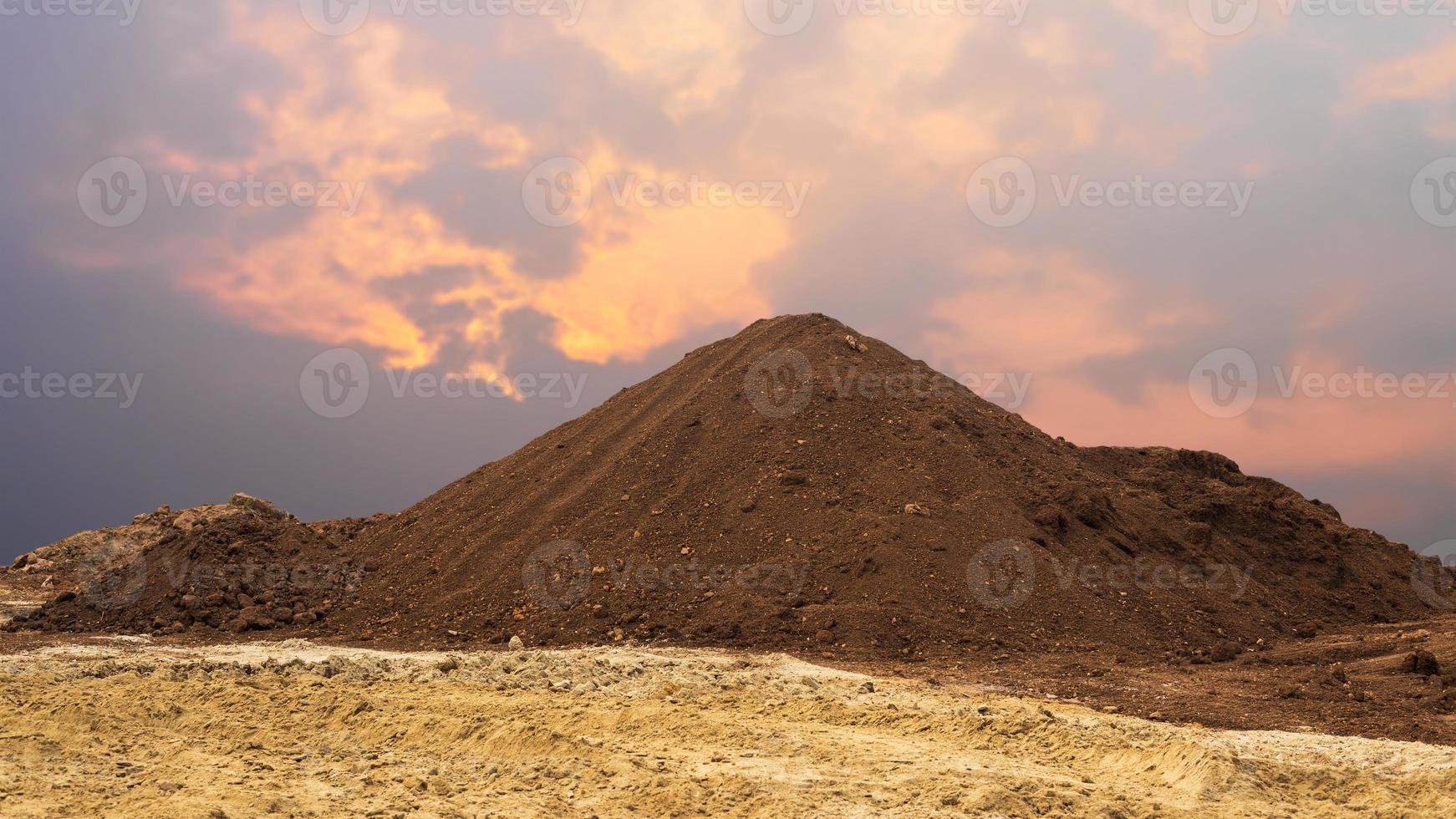 View of a large amount of brown loam loam piled up like mountains on yellow sand. photo