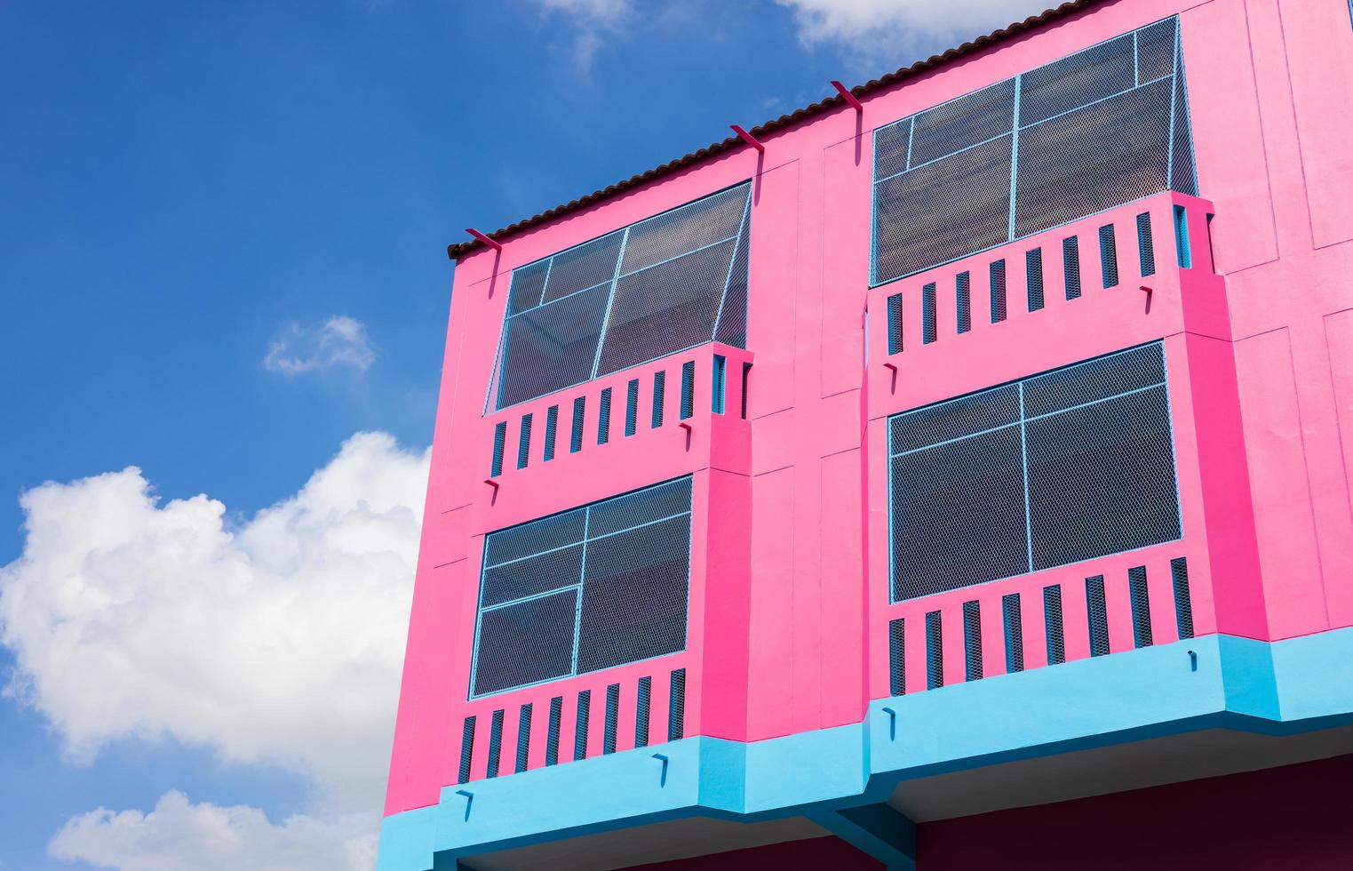 The corner of the pink building with sky clouds as a backdrop. photo