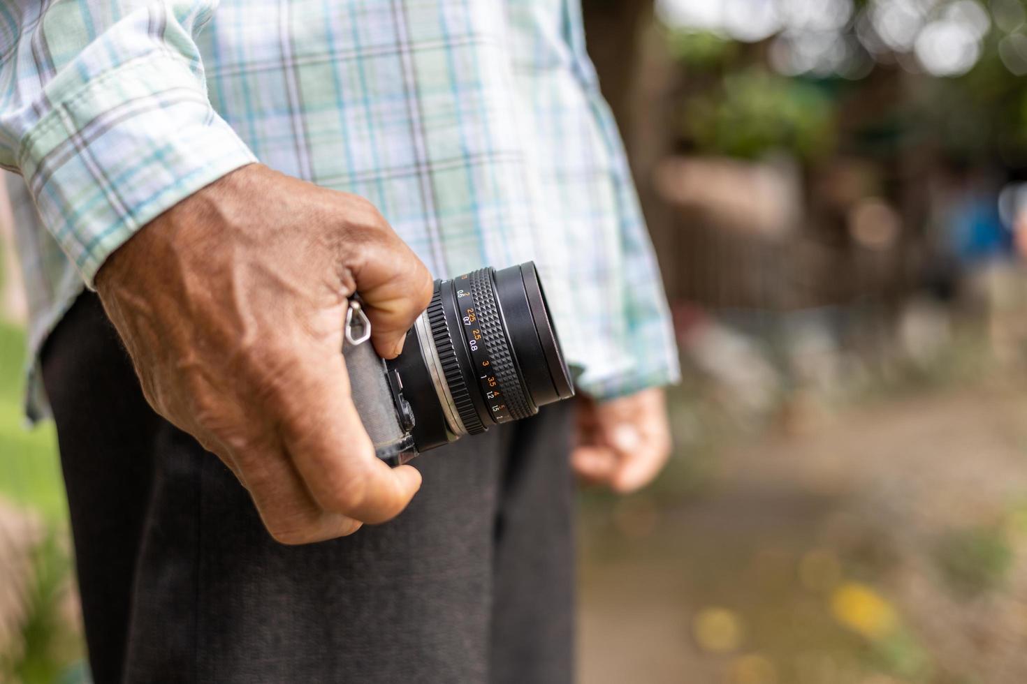 Close-up view of the elderly hand holding an old film camera. photo