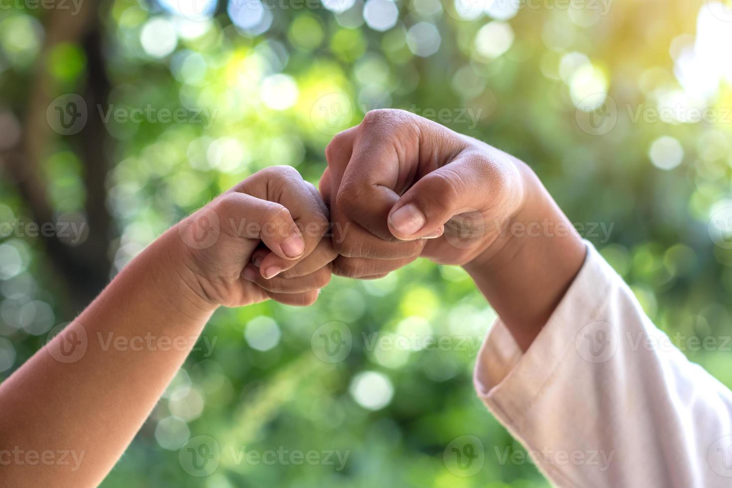 Hands fist bumps against green background blurred. photo