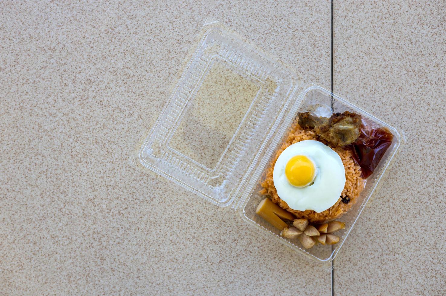 Fried egg fried rice with fried chicken in transparent plastic box. photo